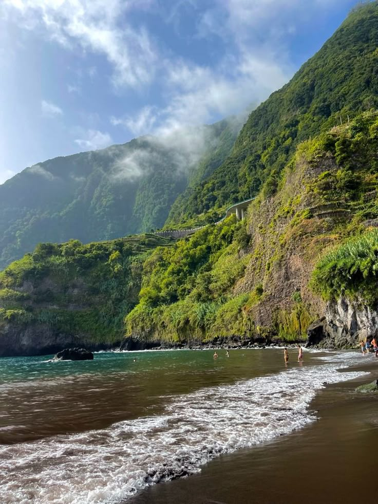 Black sand beach below green cliffs in Seixal, Madeira