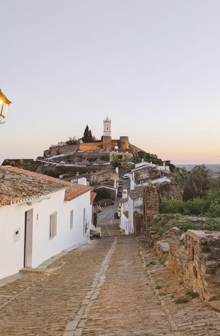Cobbled lane rising towards a hilltop village in the Alentejo at dusk