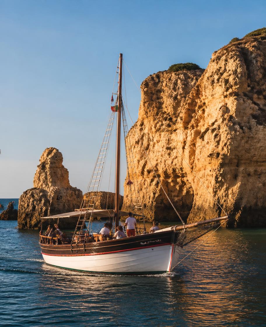A wooden boat on blue water beside Algarve limestone cliffs